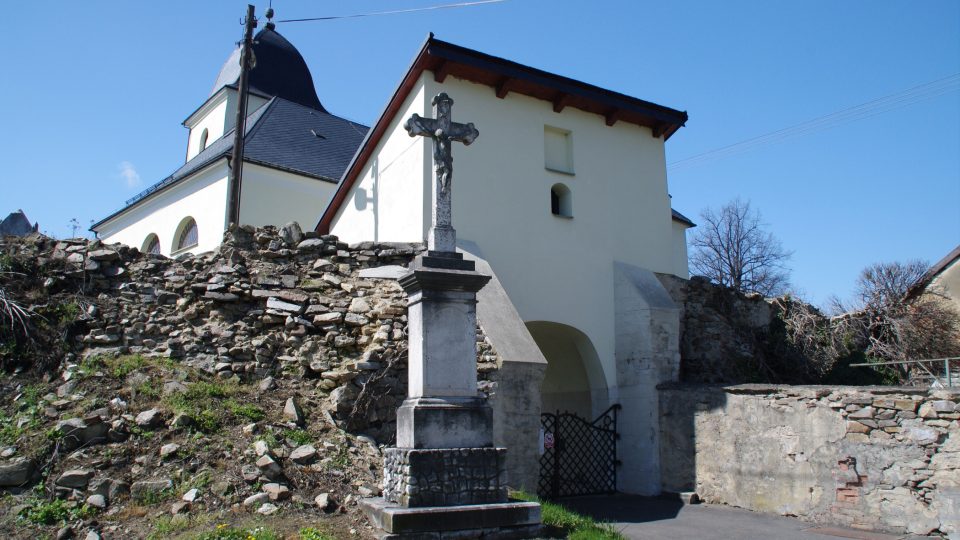 Vstup do kostelního areálu vede přes hradní bránu