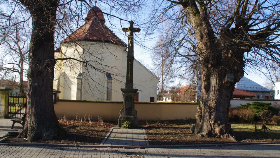 U kostelní zdi stojí i jeden z křížů,které jsou v obci k vidění.