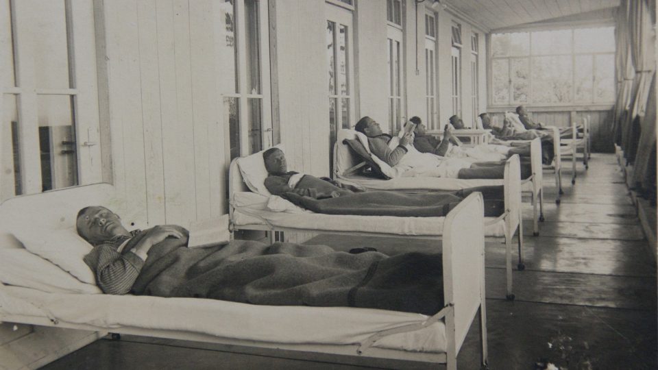 Historická fotografie z archívu léčebny ukazuje léčbu na lůžku v prostorách balkonů a otevřených pavilonů